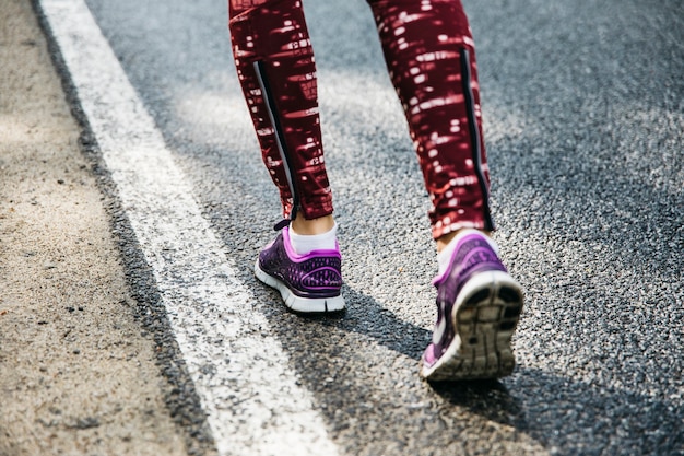 Legs of woman running on road