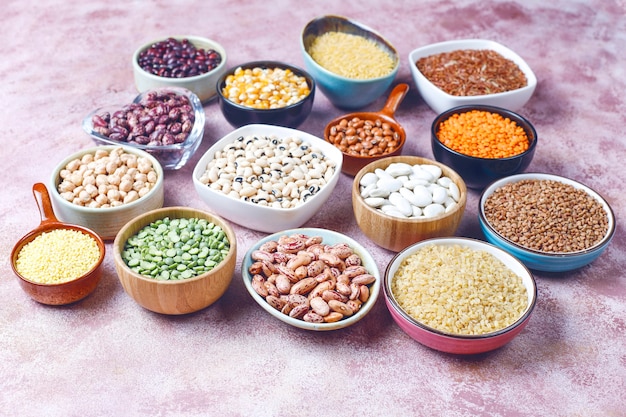 Free photo legumes and beans assortment in different bowls on light stone surface . top view. healthy vegan protein food.