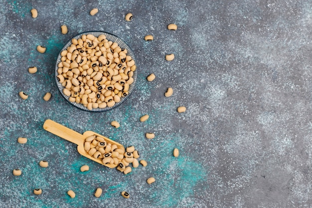 Legumes and beans assortment in different bowls on light stone surface . Top view. Healthy vegan protein food.