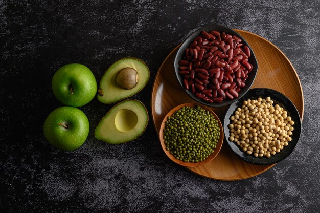 Legumes and fruit on a black cement floor.