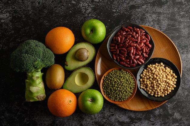 Legumes and fruit on a black cement floor.