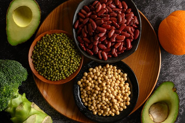 Legumes and fruit on a black cement floor.