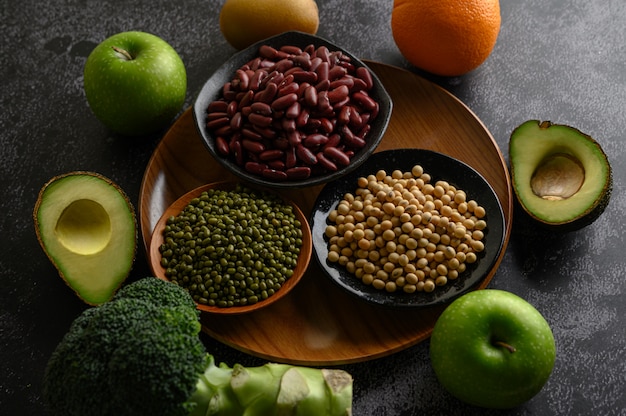 Legumes and fruit on a black cement floor.