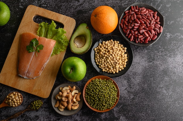 Legumes, fruit, and Salmon fish pieces on a wooden chopping board.