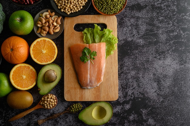 Legumes, fruit, and Salmon fish pieces on a wooden chopping board.