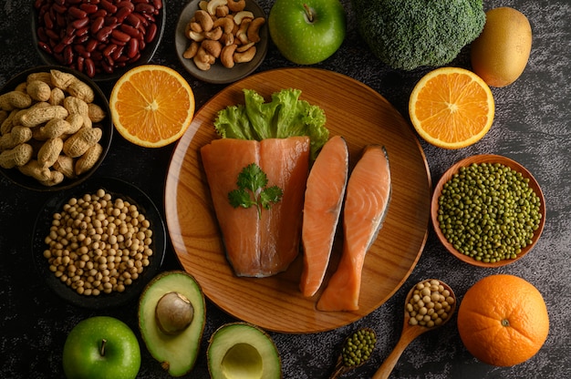 Legumes, fruit and salmon pieces on a wooden plate.