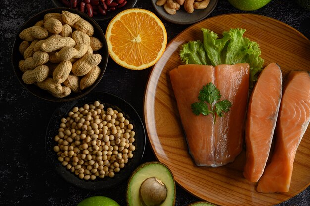 Legumes, fruit and salmon pieces on a wooden plate.