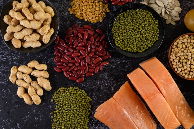 Legumes and salmon placed on a black cement floor.