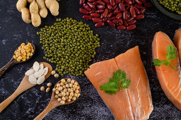 Legumes and salmon placed on a black cement floor.