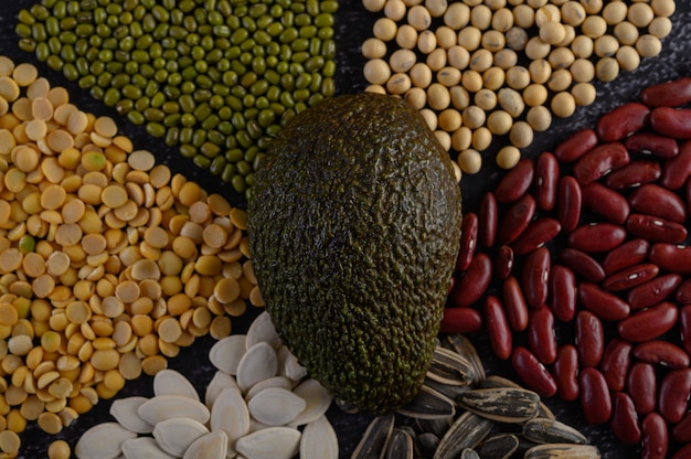 Legumes with avocado on a black cement floor surface.