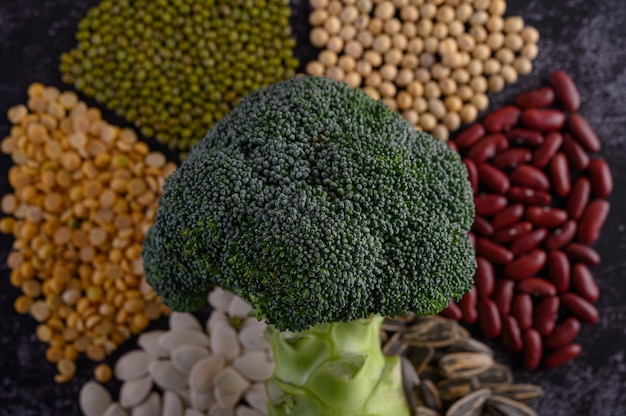 Legumes with broccoli on a black cement floor surface.