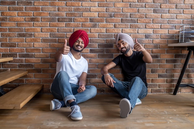 Free photo leisure. two young men sitting on the floor at home and looking relaxed