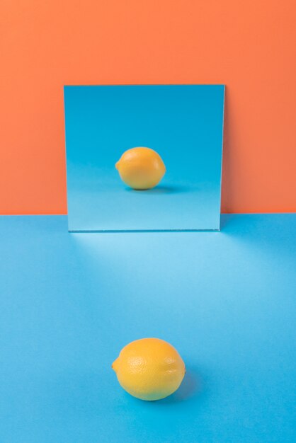 オレンジに分離された青いテーブル上のレモン