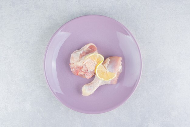 Lemon and chicken meat in the plate, on the marble surface