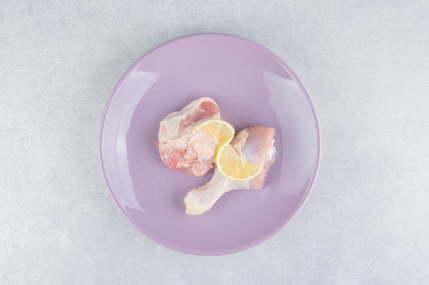 Лимонное и куриное мясо в тарелке, на мраморной поверхности