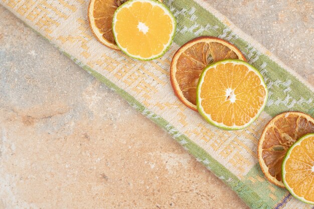 Lemon and dried orange slices on tablecloth.