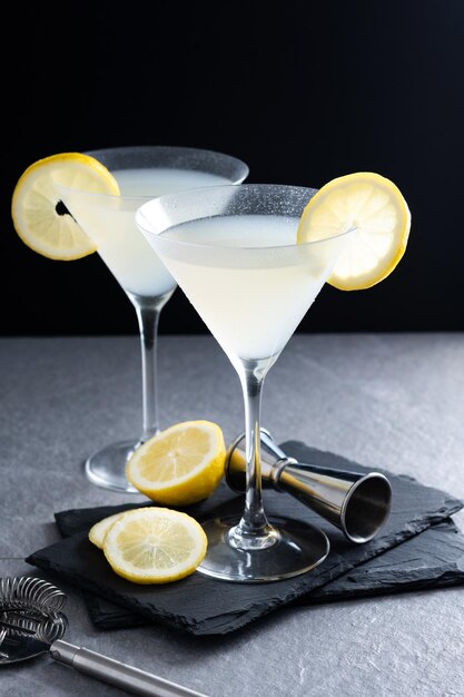 Lemon drop martini cocktail on gray stone and black background