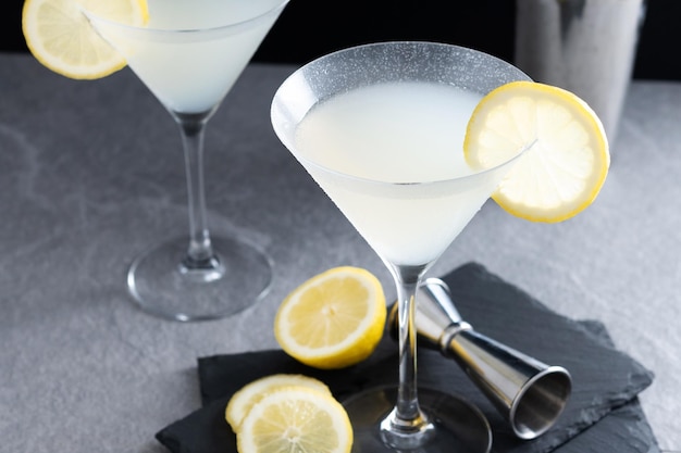 Lemon drop martini cocktail on gray stone and black background