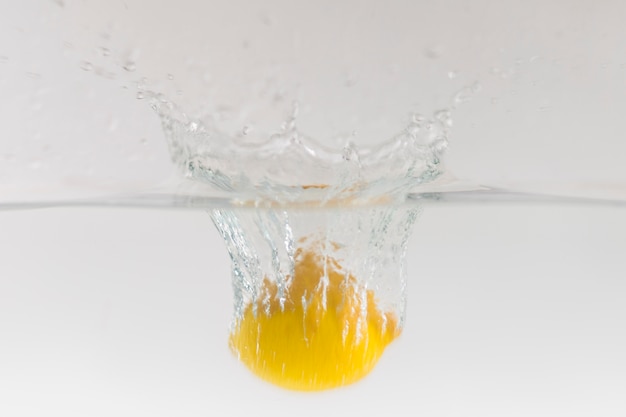 Free photo lemon falling into water