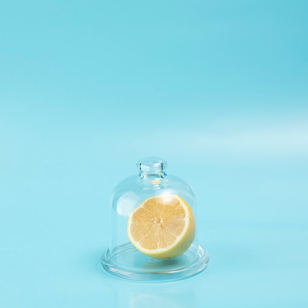Lemon in glass on blue background with copy space