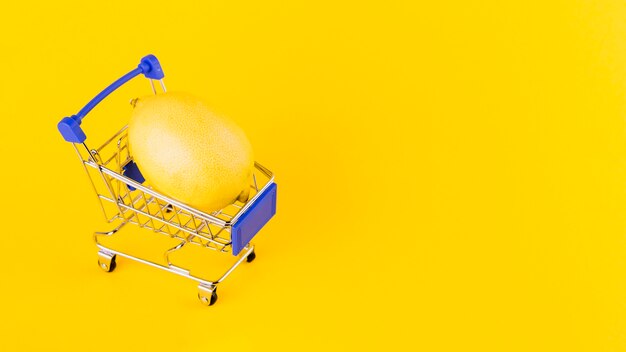 Lemon inside the shopping cart against yellow background