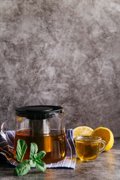 Травяной чай с лимоном и мятой в прозрачной стеклянной чашке и чайнике