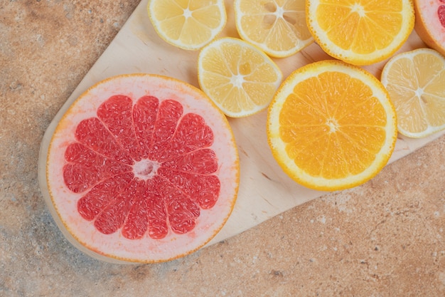 Fette di limone, arancia e pompelmo su tavola di legno.