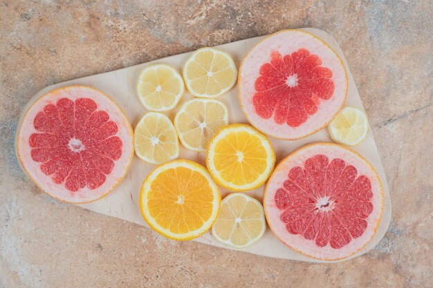 Ломтики лимона, апельсина и грейпфрута на деревянной доске.