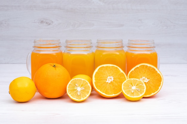 Foto gratuita limone e succo d'arancia in vetri sulla tavola bianca