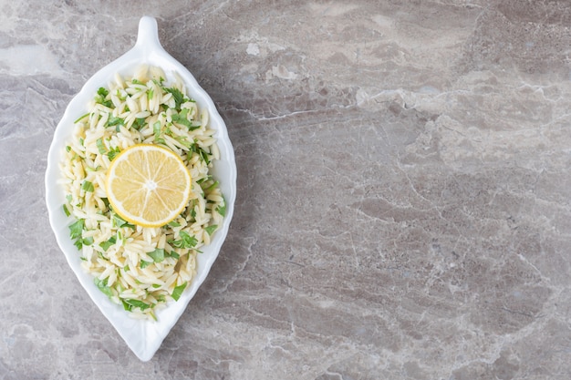 Lemon slice on pasta with green vegetables , on the marble background.