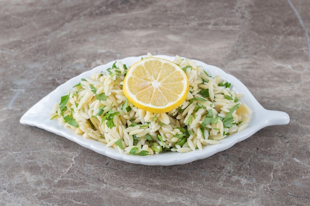 Fetta di limone su pasta con verdure, sul marmo.