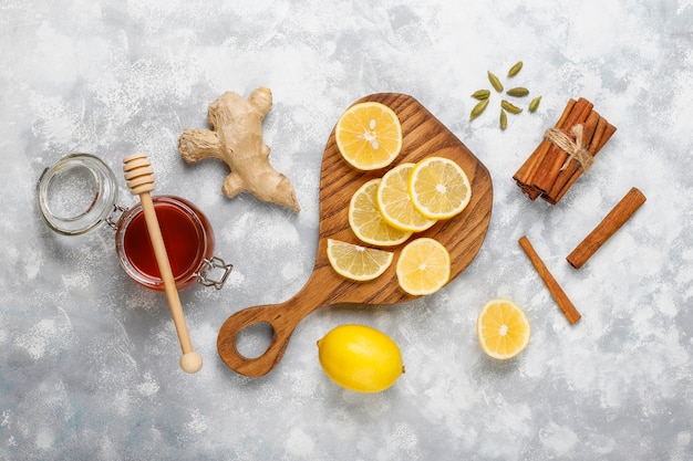 Lemon slices on cutting board,cinnamon sticks,honey on concrete  . Top view, copy space