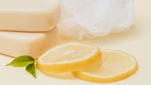 Lemon slices; soap and loofah on colored background