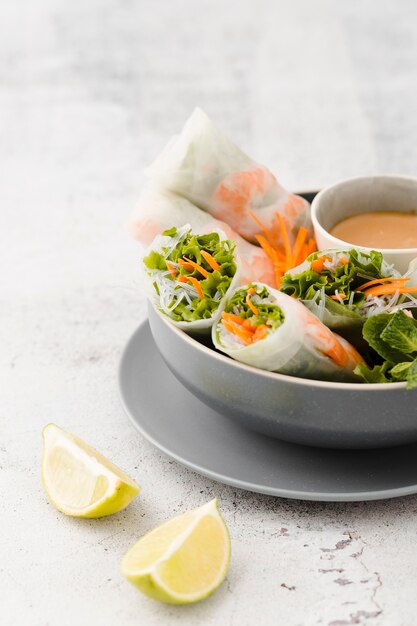 Lemon slices with bowl of shrimp rolls and salad