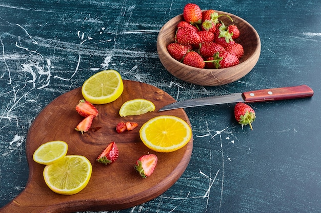 Lemon and strawberries in a wooden board. 