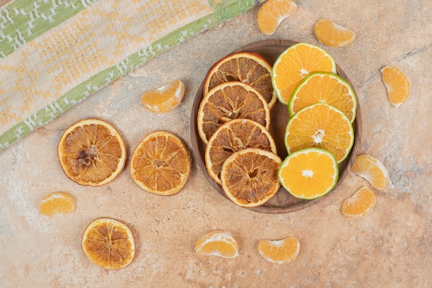 Lemon, tangerine and dried orange slices on wooden plate.