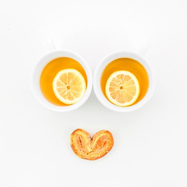 Лимонные чашки чая с пирожными Palmiers на белом фоне