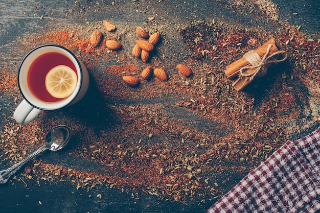 Lemon tea and dried herbs with dry cinnamon, spoon and almond flat lay