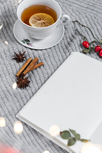 Lemon tea near notebook on knitted plaid