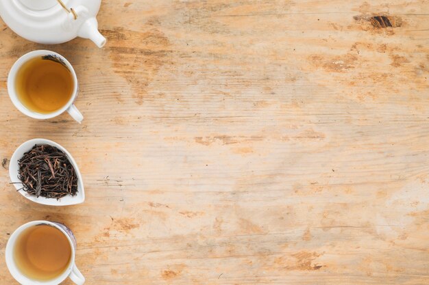 Lemon tea with dry tea leaves and teapot on wooden table