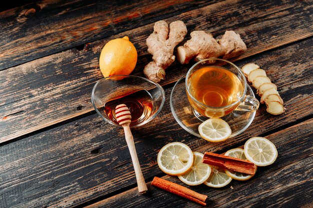 Lemon with ginger, honey, dry cinnamon, tea high angle view on a dark wooden background