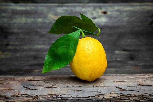 Лимон с листьями, вид сбоку на темном деревянном фоне