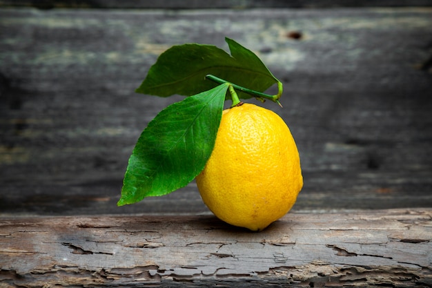 Лимон с листьями, вид сбоку на темном деревянном фоне