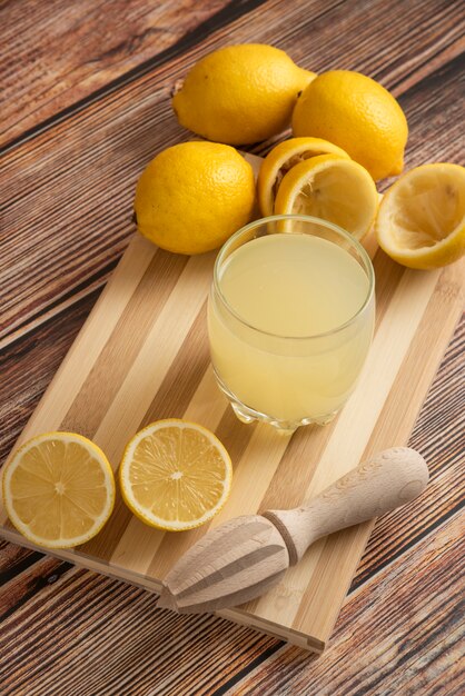 Lemonade in a glass cup on the wooden board, top view