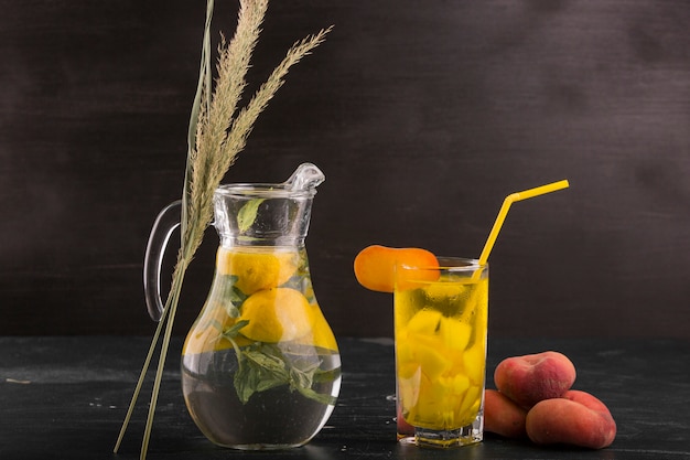 Free photo lemonade in glass and jar with peaches around