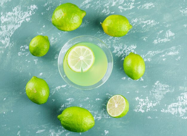 Lemonade in a glass with lemons flat lay on a plaster