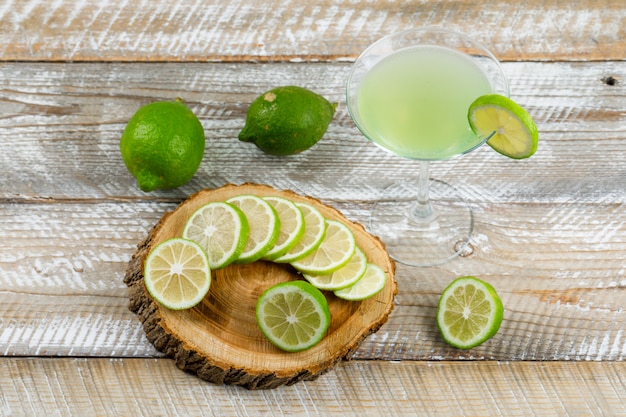 Free photo lemonade in a glass with lemons flat lay on wooden and cutting board