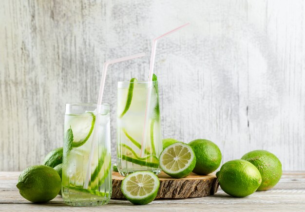 Lemonade with lemon, basil, cutting board in glasses on wooden and grungy,