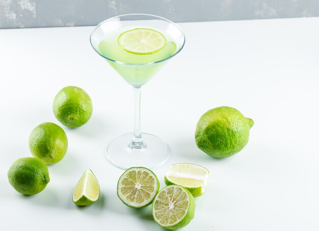 Lemonade with lemon in a glass on white and plaster, high angle view.