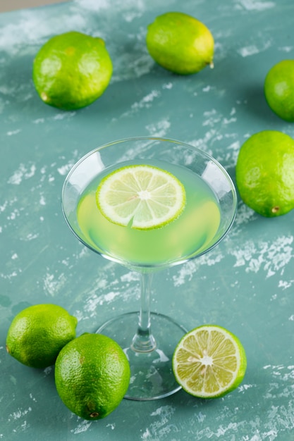 Free photo lemonade with lemons in a glass on plaster, high angle view.